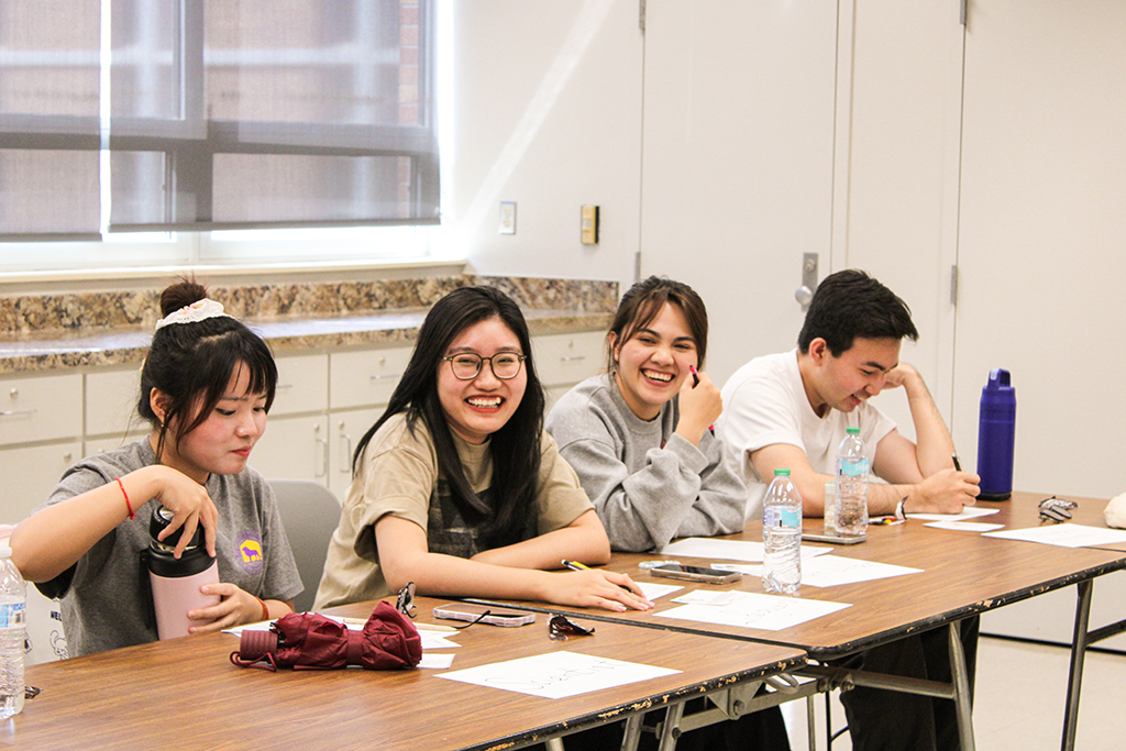 Smiling students at a desk.